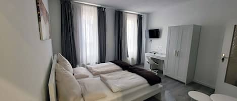 A modern bedroom with a bed, a desk, a wardrobe, and a TV.