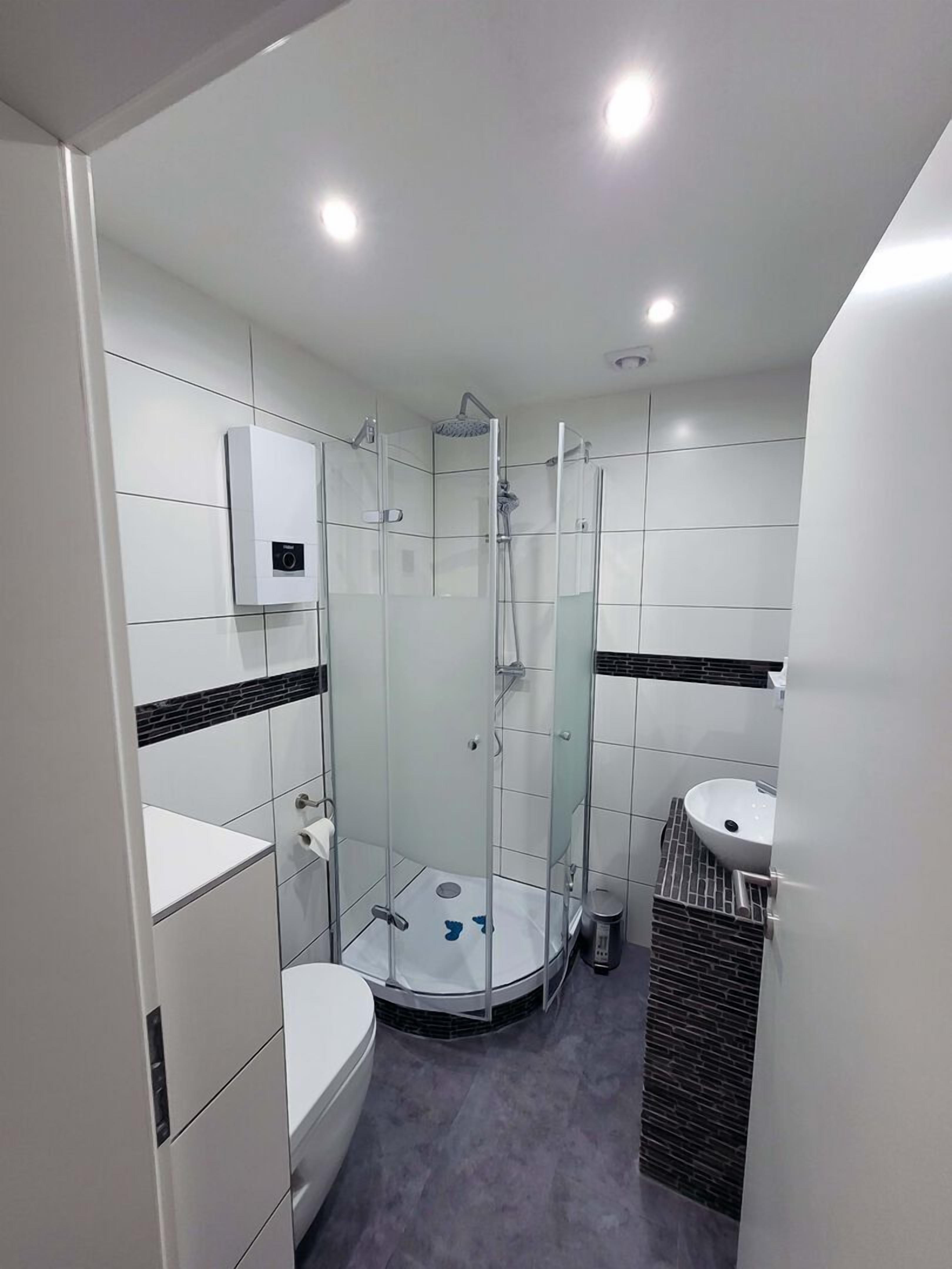 Une salle de bain moderne avec une douche à parois de verre, des toilettes et un lavabo.