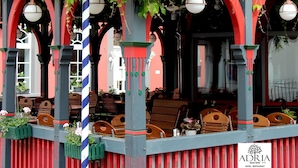 A restaurant with outdoor seating, red and blue striped columns, and hanging lanterns. - Hotel Restaurant Adria Kroatien (Bad Ems)