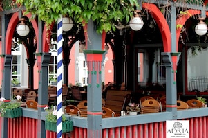 Un restaurante con terraza, columnas a rayas rojas y azules y faroles colgantes.