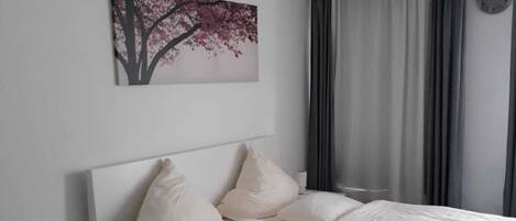 A bedroom with a bed, bedside table, and a chair.