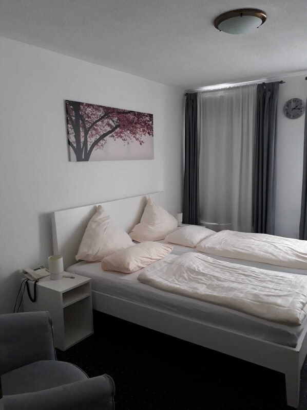 Un dormitorio con cama, mesita de noche y una silla.