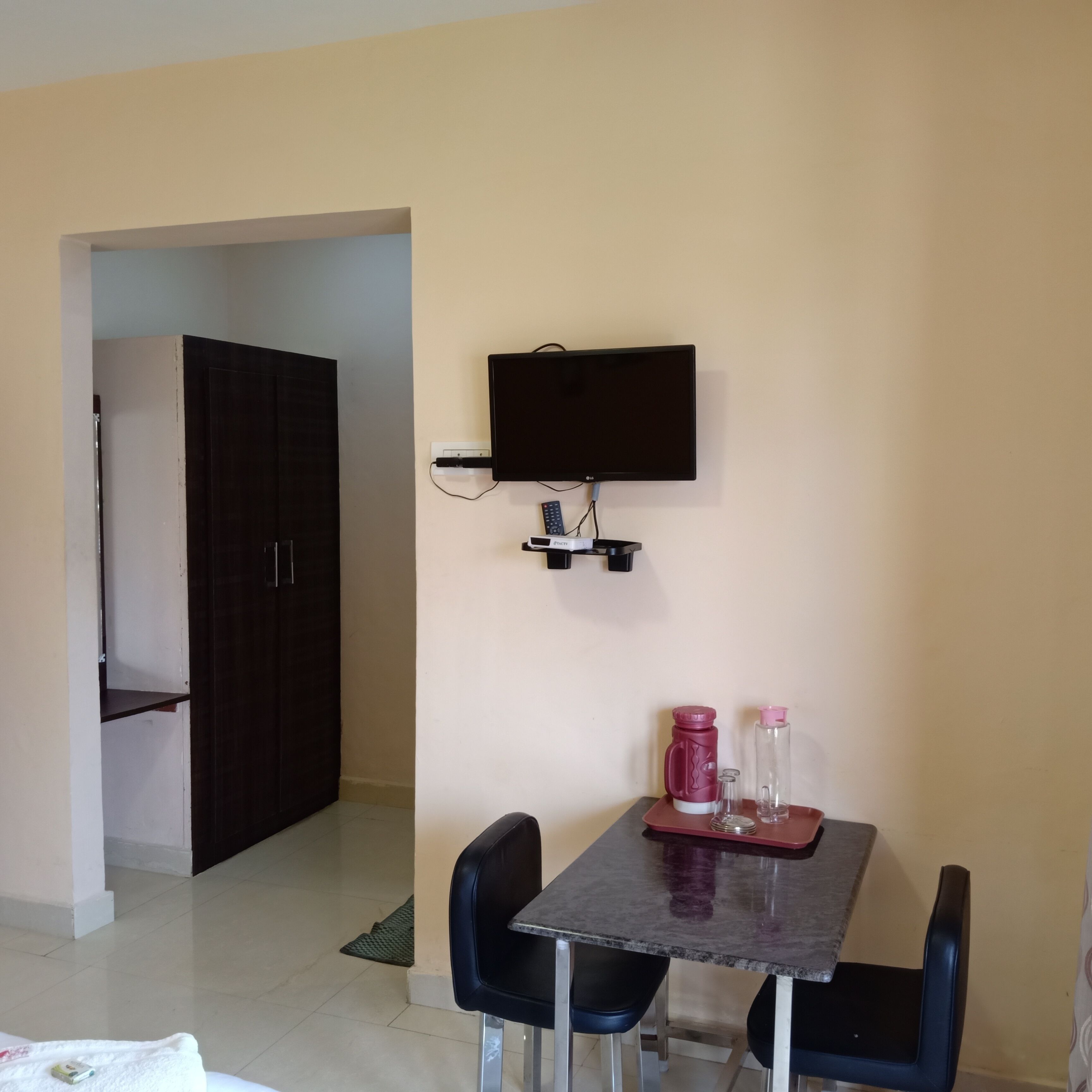 Una zona pranzo accogliente con tavolo, sedie, un televisore a parete e una porta che dà su un’altra stanza.