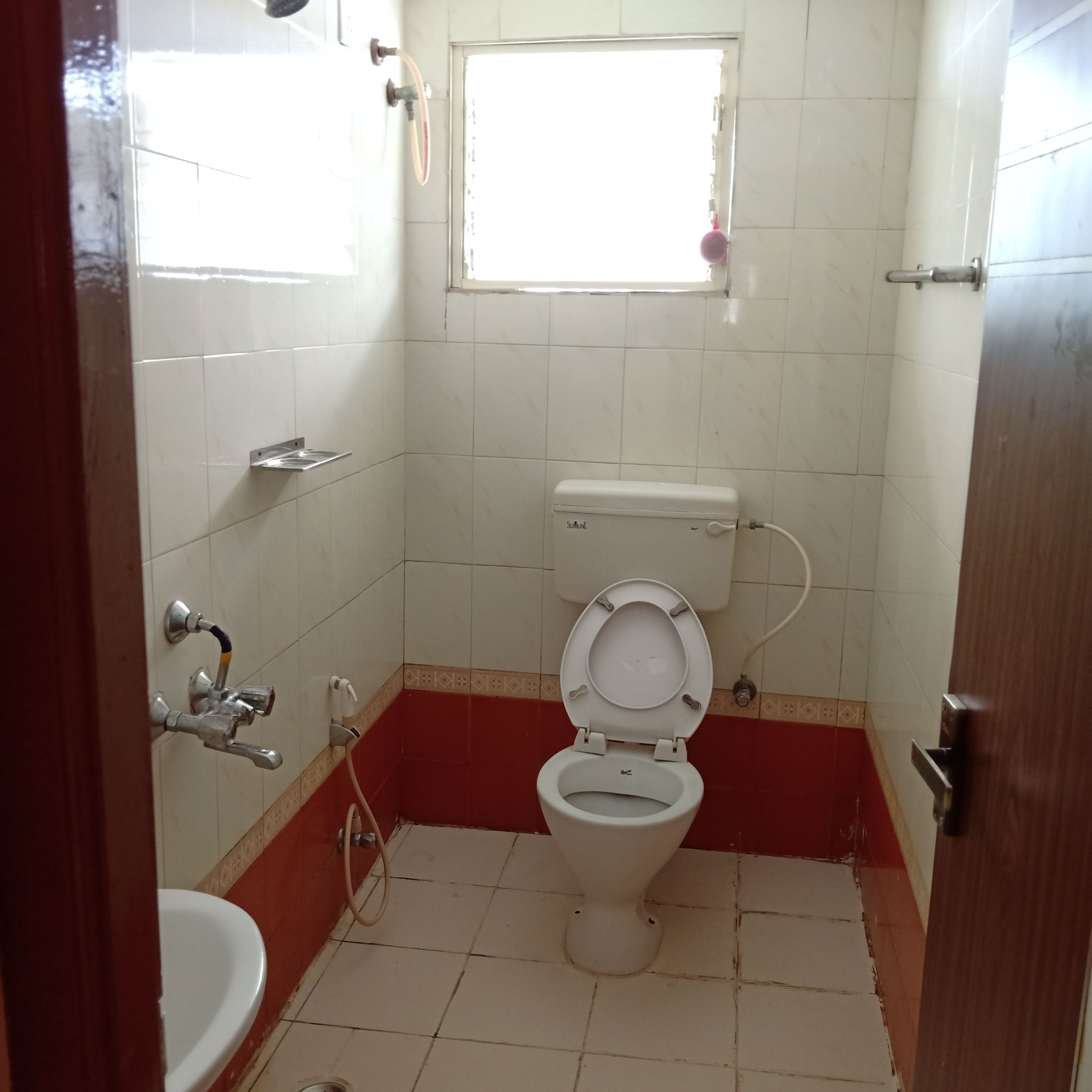 A small bathroom with a toilet, sink, and a window.