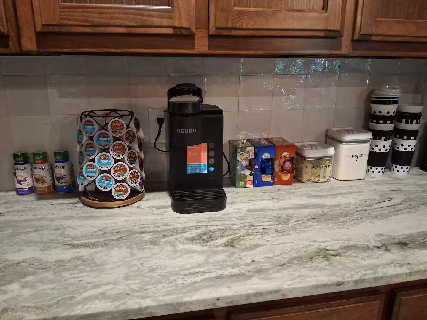 Een keukenblad met een Keurig koffieapparaat, een houder voor koffiekapsules en diverse etenswaren.