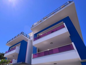 Ein modernes, mehrstöckiges Gebäude mit Balkonen und blauem Himmel.