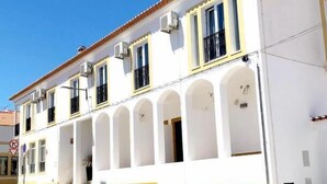 A two-story building with a white facade and yellow trim, featuring multiple windows and a central entrance with an archway. - Bulldog Inn Duna Parque Resorts & Hotels (Odemira)