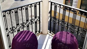 A balcony with two purple poufs, a white column, and a view of a street with buildings. - Bulldog Inn Duna Parque Resorts & Hotels (Odemira)
