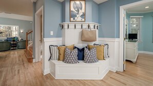 A room with a white bench, blue walls, and a wooden floor. - Spacious 7B, 4BA Family Retreat with Game Room & Two Primary Suites! Pool, WIFI, Tennis, Shuttle to the Beach! (Ocean View)
