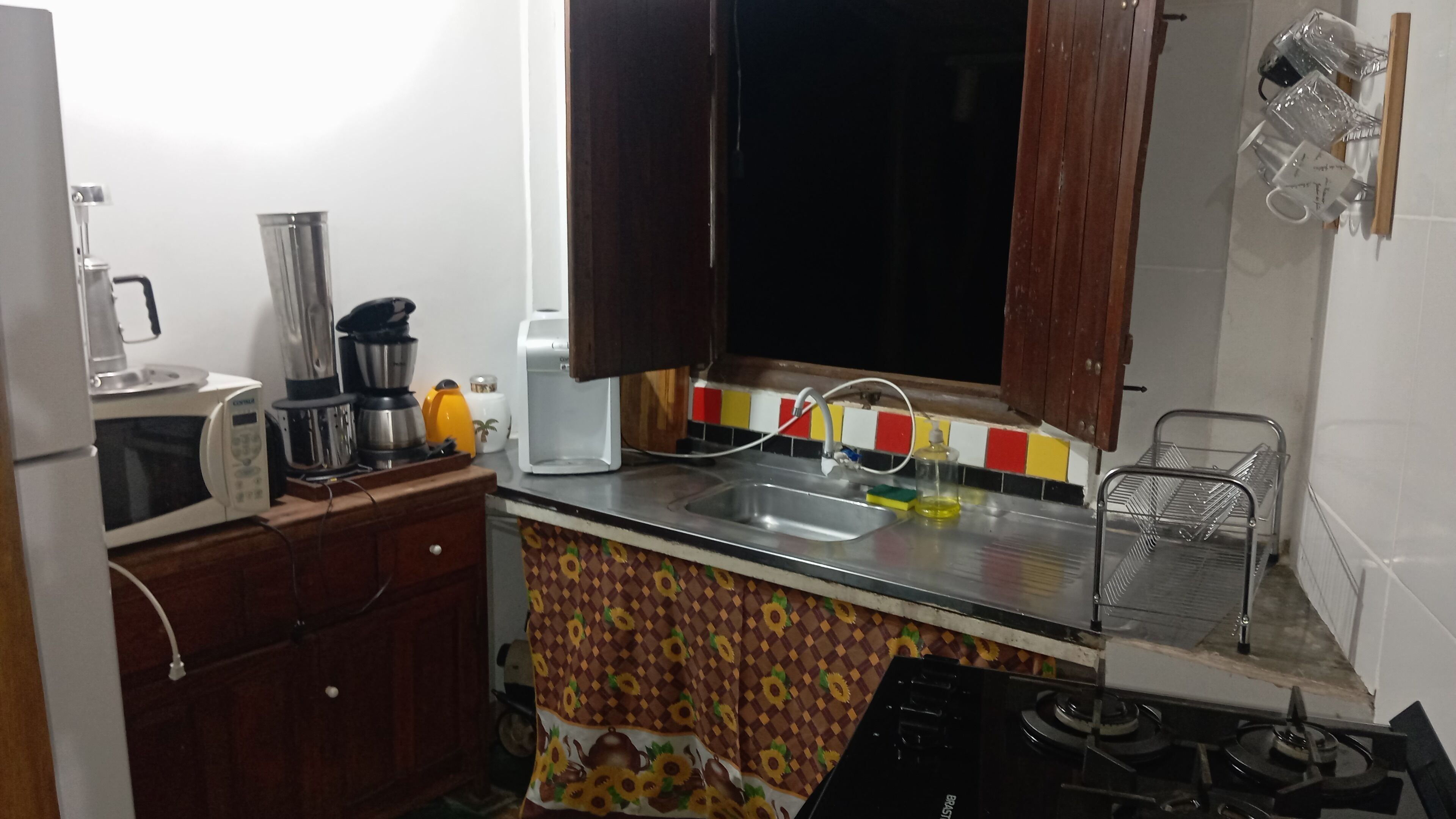 Eine kleine Küche mit Mikrowelle, Kaffeemaschine und Gaskochfeld.