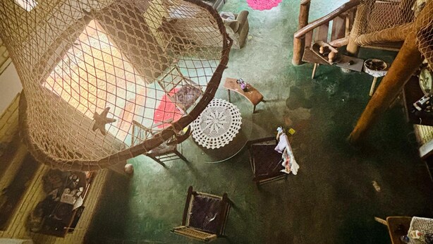 A high-ceiling room with a netted play area, a sofa, a round table, and a staircase. - A rustic and charming chalet nestled among centuries-old Jatobá trees! (Piraputanga)