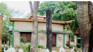 A two-story building with a brick facade and green trim, surrounded by lush greenery and trees. - A rustic and charming chalet nestled among centuries-old Jatobá trees! (Piraputanga)