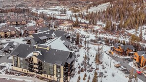 Un hôtel moderne à plusieurs étages, avec une station de ski en arrière-plan et un paysage montagneux.