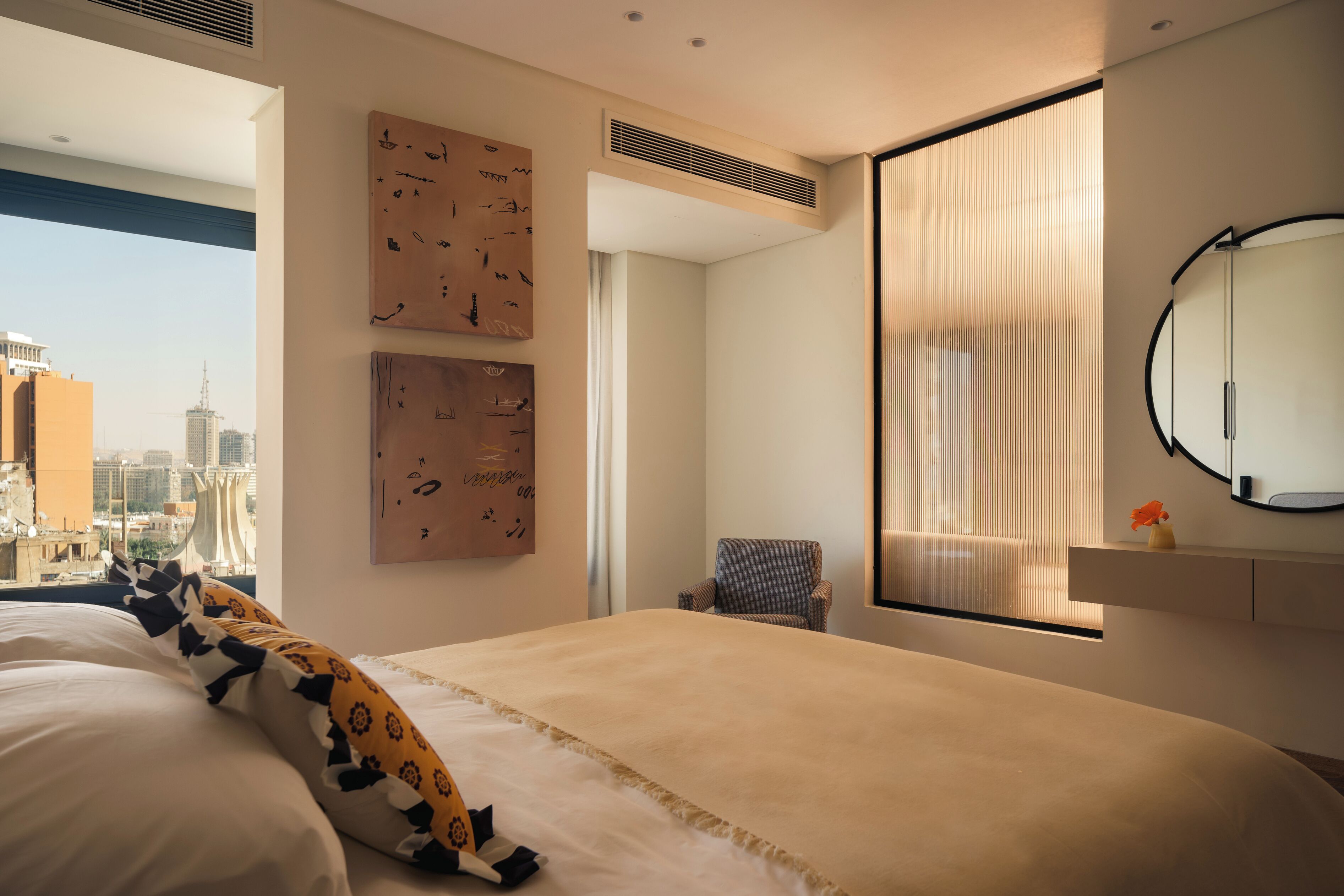 Ein modernes Hotelzimmer mit einem großen Bett, einem Sessel, einem Fenster mit Jalousien und einem Kunstwerk an der Wand.