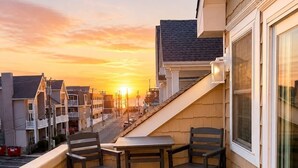 Ein Balkon mit Tisch und Stühlen, der auf eine Straße mit Sonnenuntergang Blick bietet.