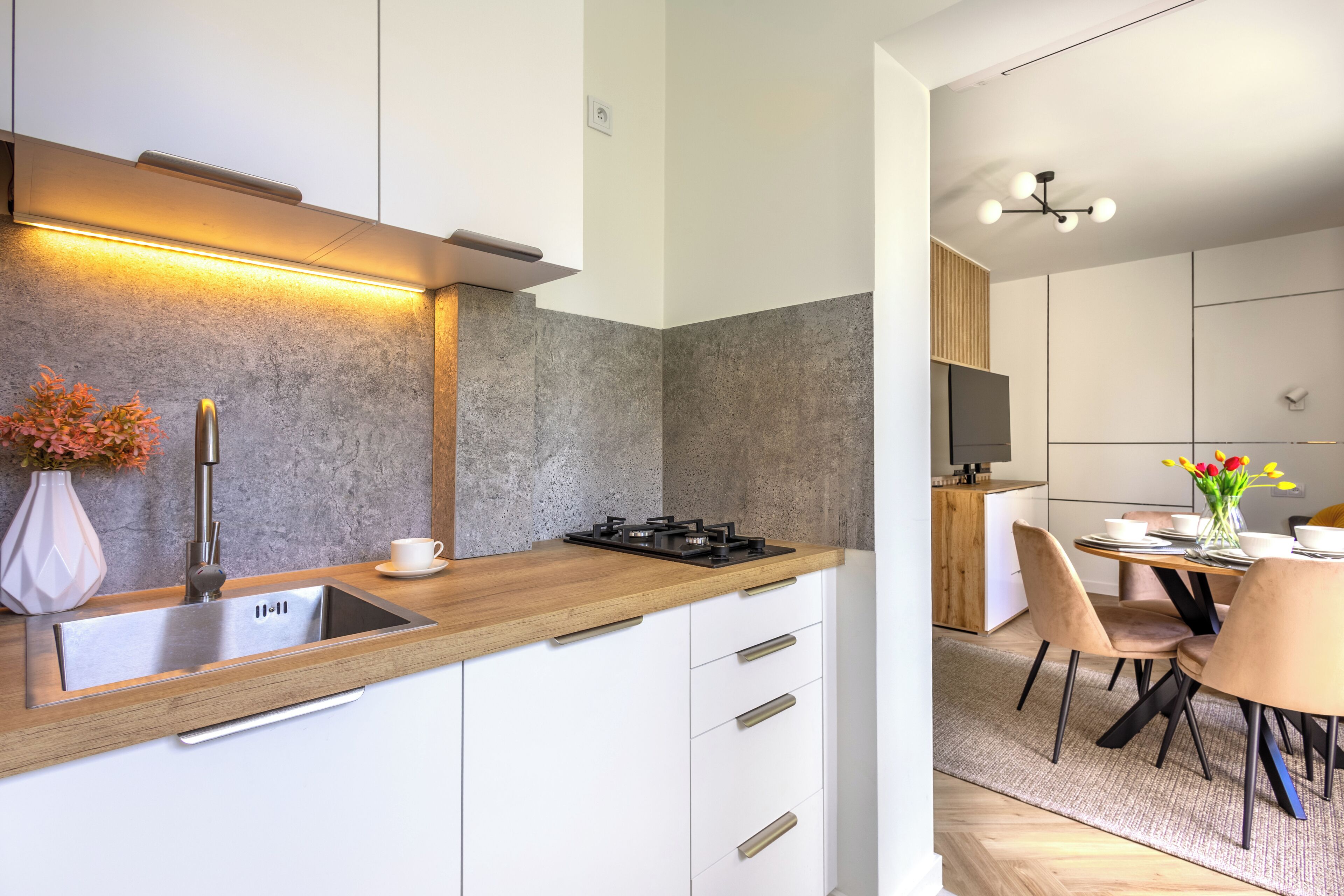 A modern kitchen with a stainless steel sink, wooden countertop, and a built-in stove.