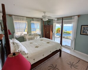 Un dormitorio con cama, escritorio, silla, armario y vistas al mar.