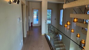 A modern interior with a wooden staircase, glass railing, and a view to the outside. - Serene,  spacious 4-bedroom villa in beautiful Pelion, located on the west side (Artemis)