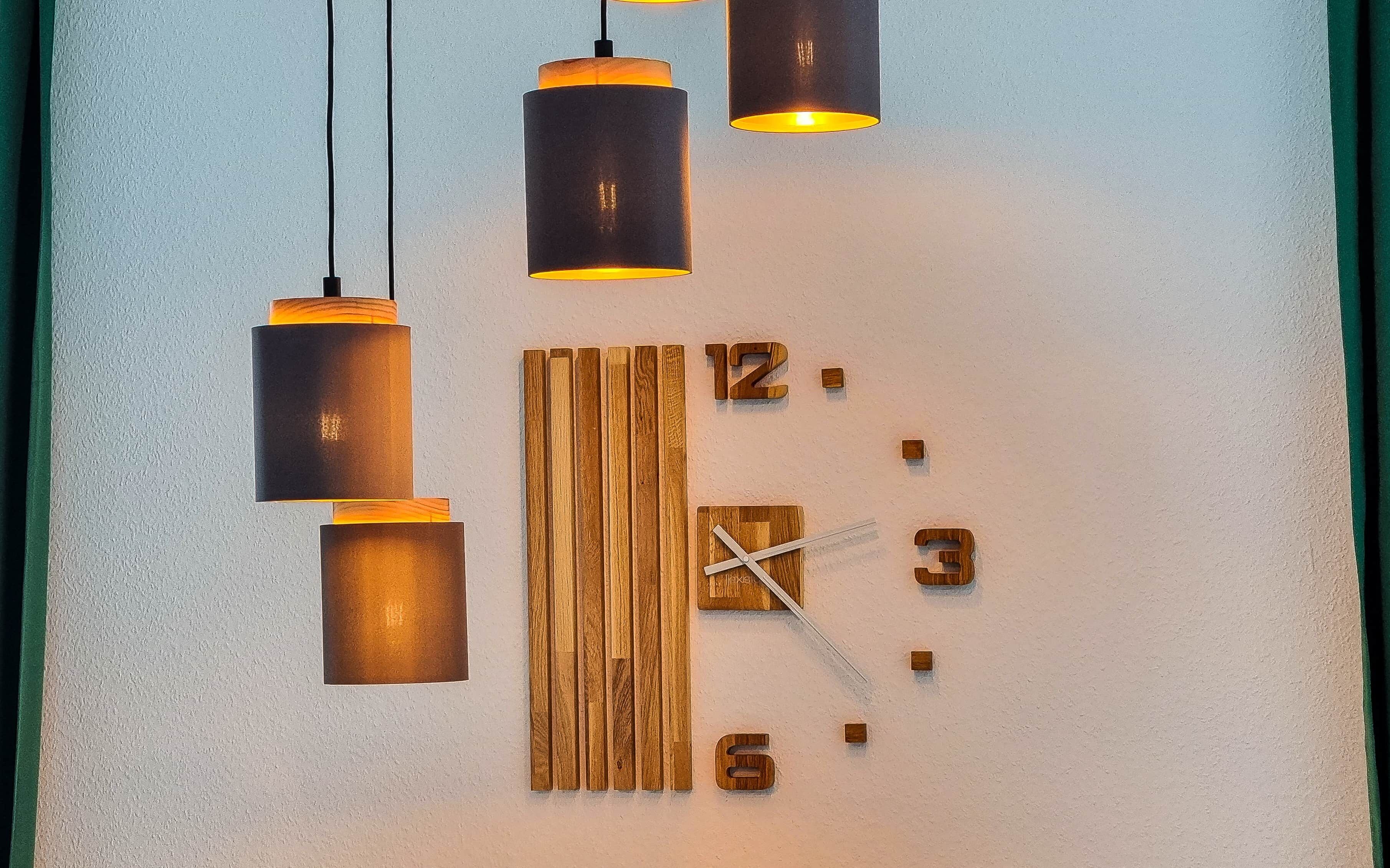 A wall clock with a wooden panel design, three hanging pendant lights, and a number '12' visible on the wall.