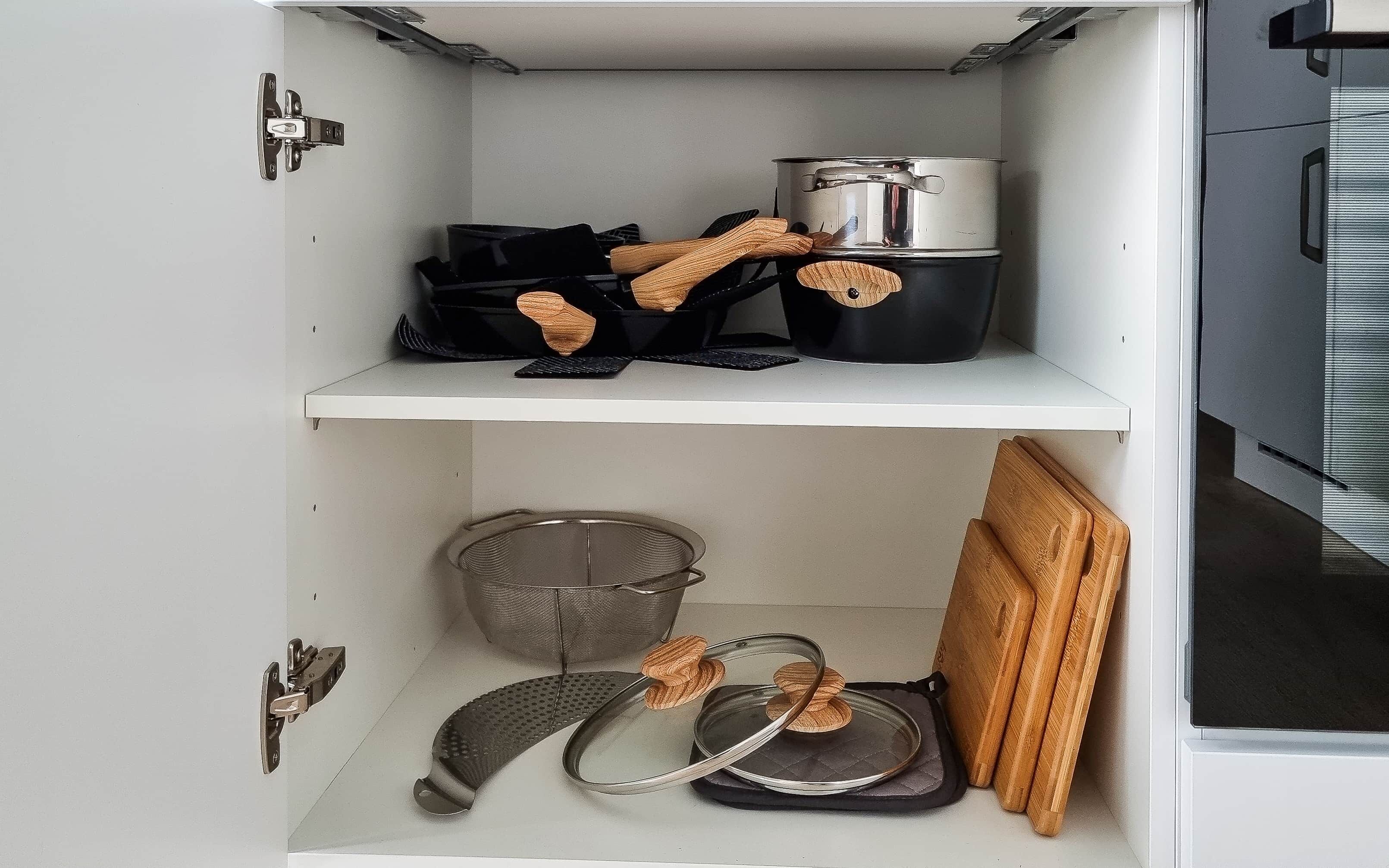 Una cuina amb una olla a l'estant superior i un colador a l'estant inferior.