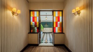 A hallway with a checkered floor, striped walls, and two wall-mounted lamps. - Longchamps Hotel (Cairo)