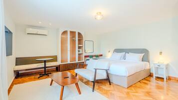 Una habitación de hotel moderna con una cama, un sofá, una mesita, un banco y un armario.