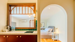A hotel room with a wooden cabinet, a mirror, a bed with white bedding, a bedside table with a lamp, and a herringbone-patterned floor. - Longchamps Hotel (Cairo)