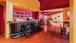 A restaurant with a bar area, red walls, and a tiled floor. - Longchamps Hotel (Cairo)
