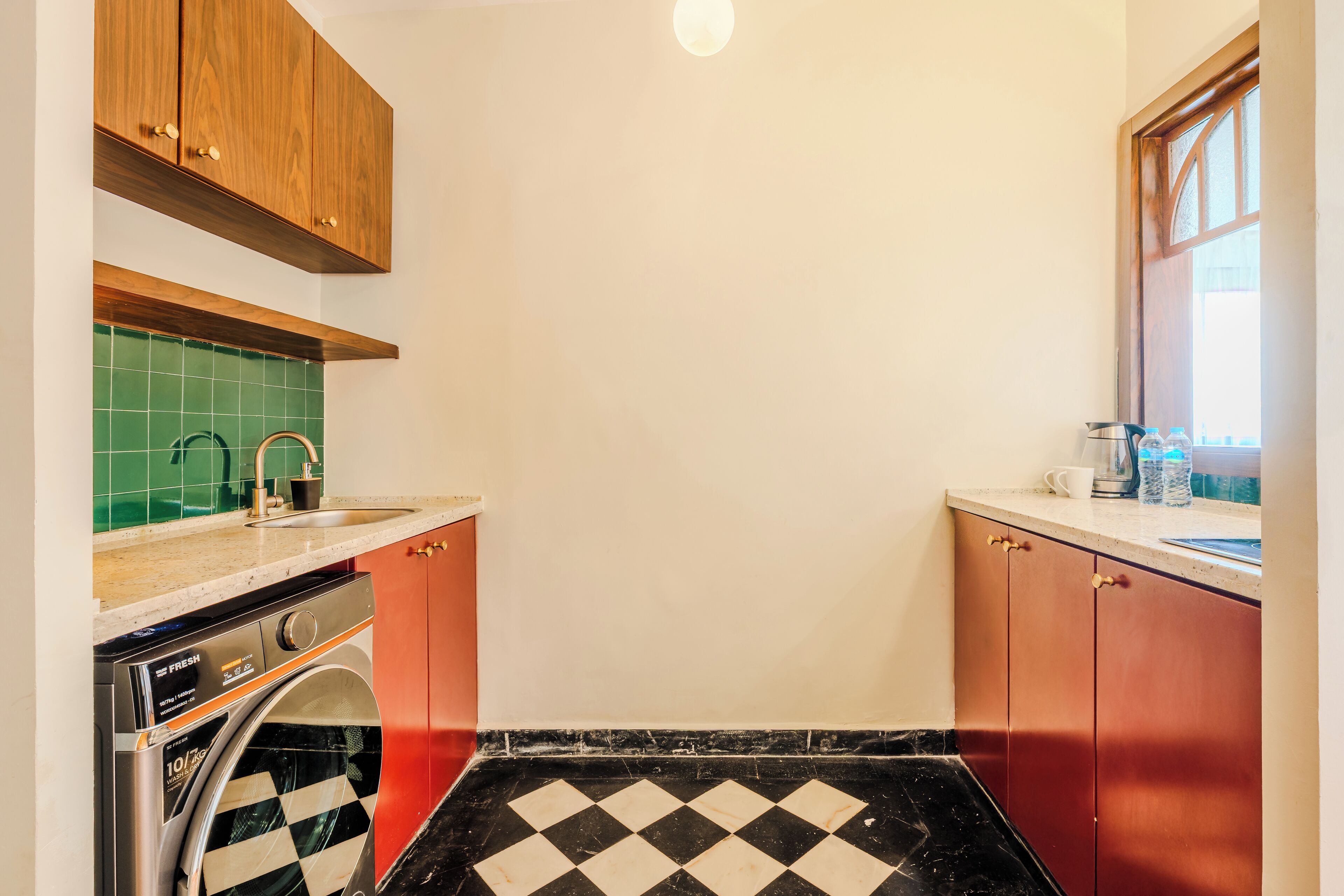A compact kitchen with a washing machine, a sink, and a window.