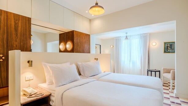 A hotel room with two beds, a wooden wardrobe, a bedside telephone, and a small table. - Longchamps Hotel (Cairo)
