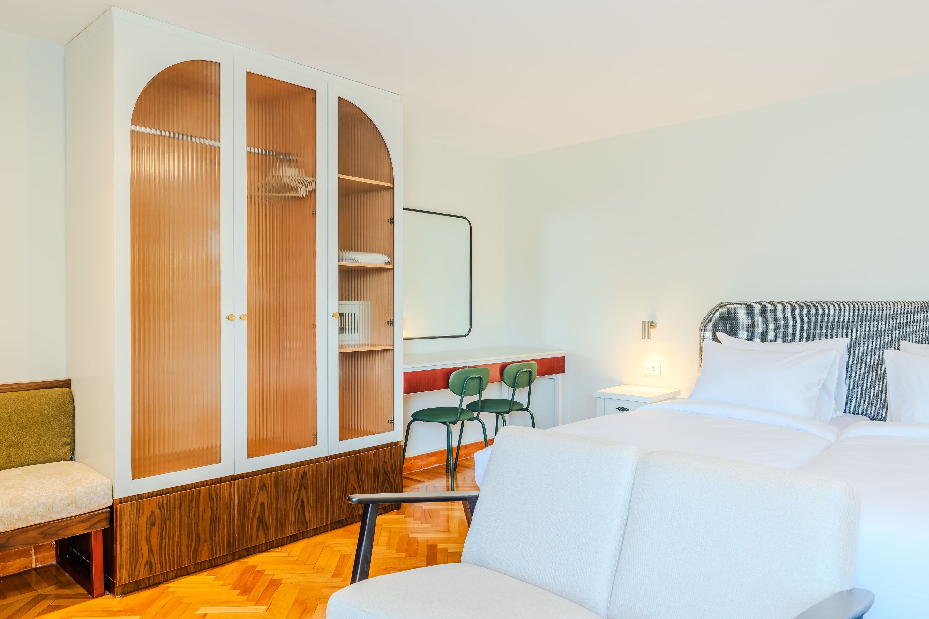 A hotel room with a bed, a wardrobe, a desk, and a chair.
