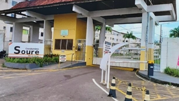 Uma entrada gradeada para um edifício com uma placa que diz 'Soure Condomínio'.