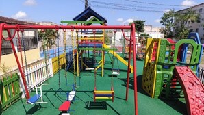 Um parquinho com diversas estruturas de recreação e uma área cercada.