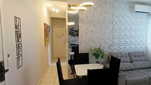 Uma sala de estar moderna com uma mesa de jantar, cadeiras, um sofá e uma parede estampada.