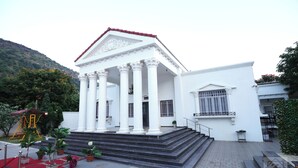 Un bâtiment blanc doté d’un portique et d’un escalier menant à une porte.