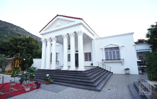 Um edifício branco com pórtico e degraus que levam a uma porta.