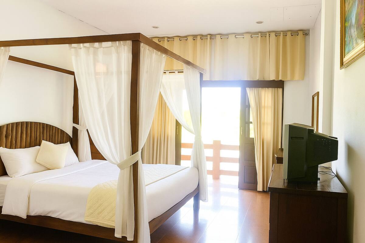 Una cama con dosel, ropa de cama blanca, cabecera de madera y cortinas de encaje.