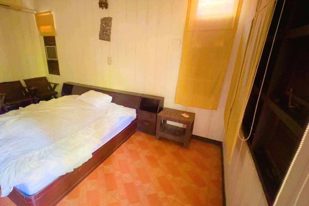 Habitación de hotel con una cama grande, una mesita, una silla y una mesita de noche.