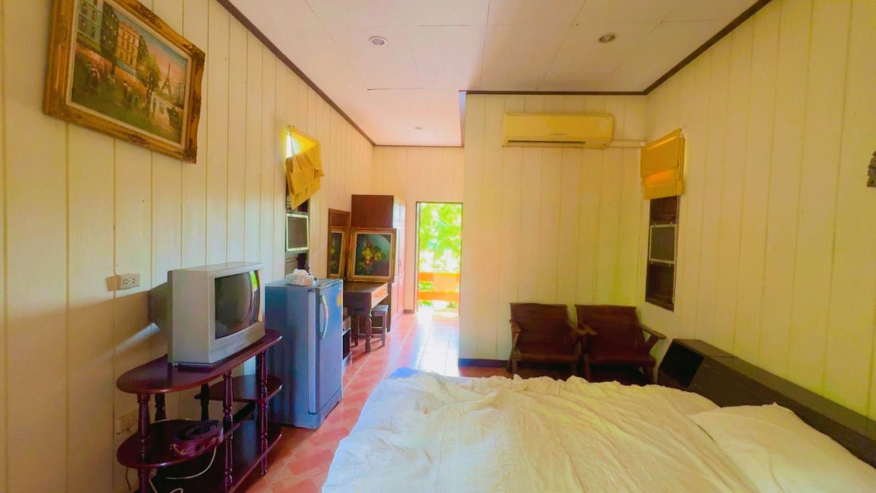 Une chambre d’hôtel équipée d’un lit, d’une télévision, d’un réfrigérateur, d’un bureau et d’une chaise.