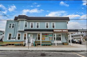 A two-story building with a sign reading "Bungalow Bowls." There are benches outside and a staircase leading to the entrance. - Heart of Downtown OC- Steps to Shopping, Eating, Beach, Boardwalk. On Asbury (Ocean City)