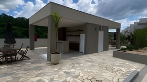A modern outdoor patio area with a stone-tiled floor, a covered seating area, and a potted plant. - Benno Prime Loft (Extrema)
