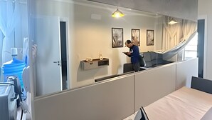 A modern hotel room with a large mirror, a desk, and a chair. There are framed pictures on the wall and a window with curtains. - Benno Prime Loft (Extrema)