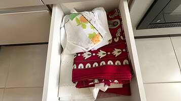 A drawer with neatly folded clothes, including a white garment with a leaf pattern and a red garment with white designs.