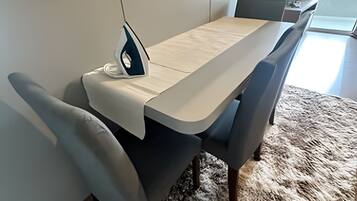 Un espace repas comprenant une table, des chaises et un fer à repasser.