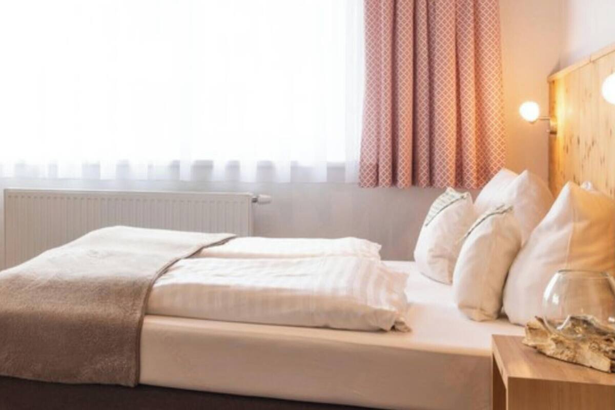 Ein Hotelzimmer mit Bett, Schreibtisch und Laptop sowie einem an der Wand befestigten Fernseher.