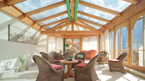 A sunlit room with wicker furniture, a round table, and large windows. - Pitztal Living (Jerzens)