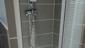 A glass-enclosed shower with a tiled wall and a showerhead.