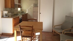 A compact kitchen with wooden cabinets, a dining table, and a chair.