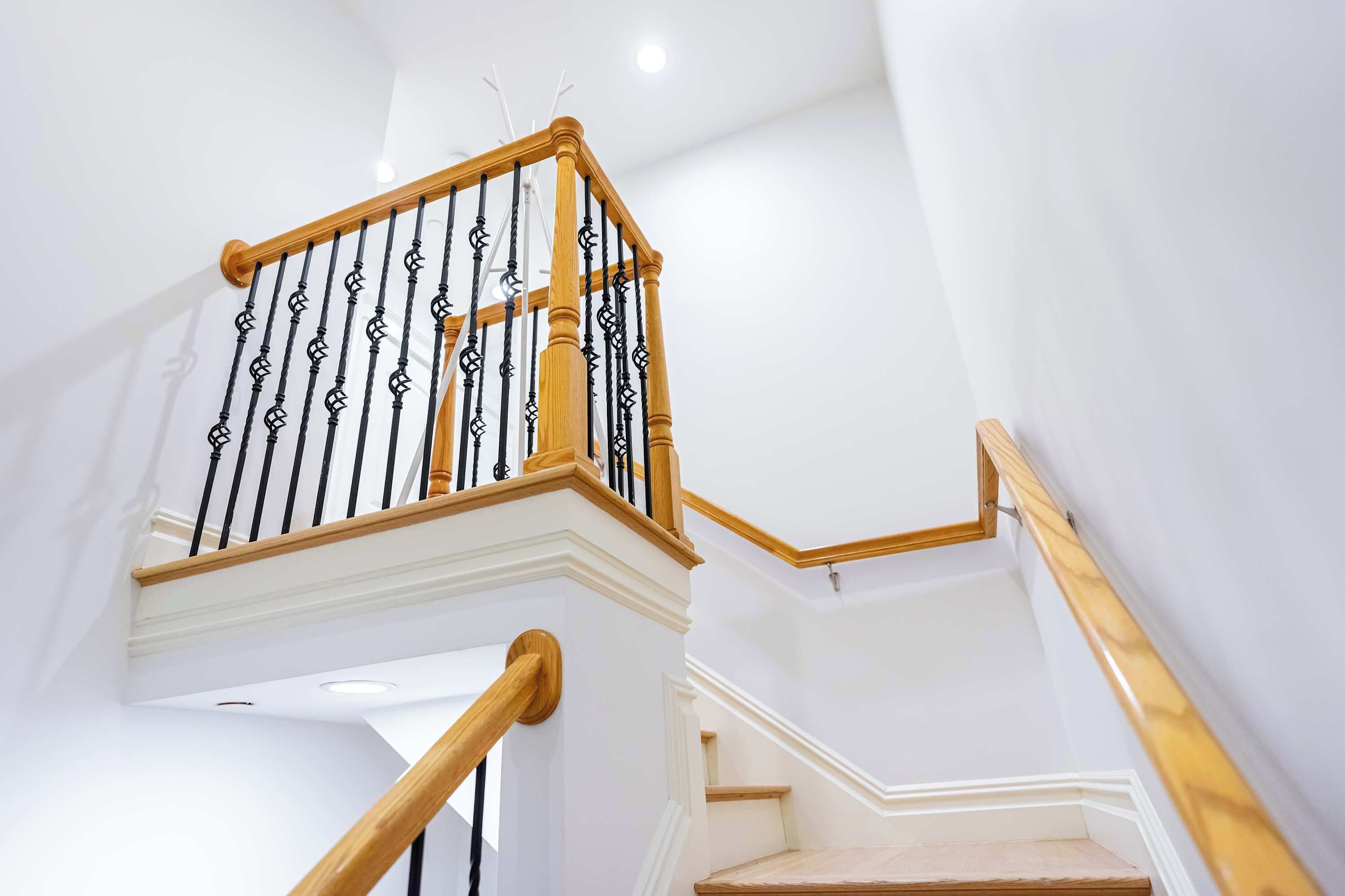 A staircase with wooden handrails and black balusters.
