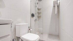 Une salle de bain moderne équipée de toilettes, d’une douche et d’un espace de douche vitré.